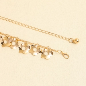 Detail of golden metal waist chain featuring floral pendants and adjustable lobster clasp