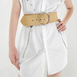 Detail of woven straw belt with large silver round buckle on white dress model