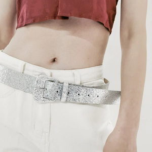 Close-up of sparkling silver Y2K glitter belt with square buckle on white jeans