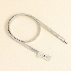 Close-up of silver metal elastic waist chain with a sparkling rhinestone bow buckle
