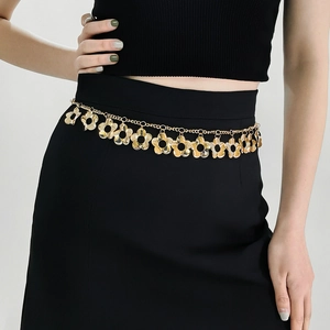Detailed view of a golden metal waist chain with floral charms and polished finish
