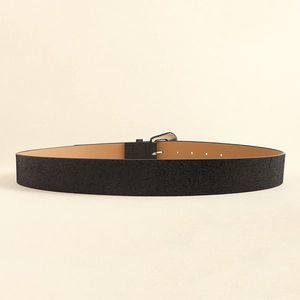 Detail view of wide black leather belt with silver buckle and adjustable holes for jeans
