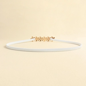 Detail of white elastic waist belt with elegant gold floral metal buckle for women