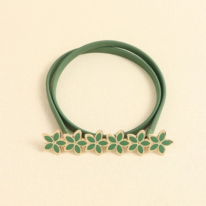 Close-up of green grass elastic waist chain with enamel flower design and rhinestones