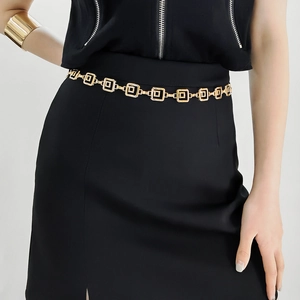 Détail d'une ceinture chaîne dorée de luxe avec carrés géométriques sur robe noire