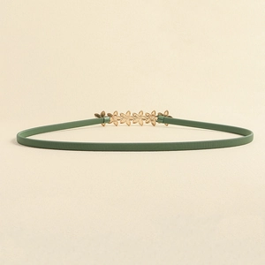 Detail of green elastic waist belt featuring a gold floral metal buckle and fine texture