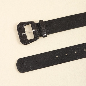 Detail of Y2K style black sequin belt featuring a matching square buckle on beige background