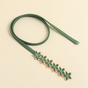Detail of green enamel flower buckle on elastic gold-plated metal waist belt for women
