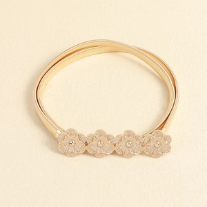 Elegant gold stretch belt with intricate cutout flower buckle on a textured surface