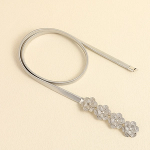 Detail of silver elastic metal waist chain featuring intricate cutout flower buckle design