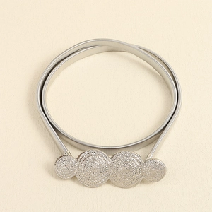 Detail view of silver stretch metal belt with textured circular plates and spring structure
