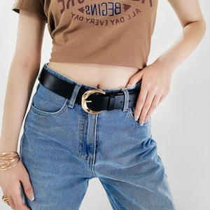 Close-up of a studded black leather belt with golden crescent buckle on denim jeans