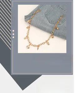 Détail de la chaîne de pantalon dorée avec breloques coquillages sur un jean