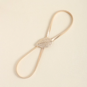 Detail of golden leaf metal buckle with textured veins and elastic stretchable cord
