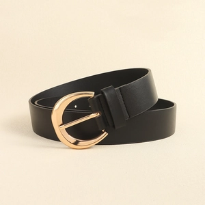Detail of minimalist black leather belt for women featuring a polished gold round buckle