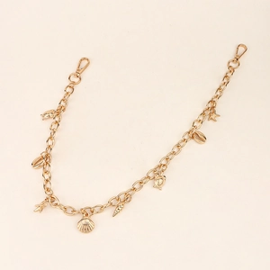 Détail d'une chaîne punk dorée avec pendentifs coquillages, étoiles de mer et tortues