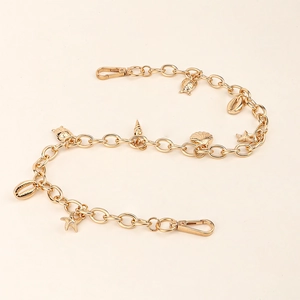 Détail de la chaîne de pantalon dorée avec pendentifs coquillage et étoile de mer