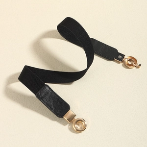 Détail d'une ceinture élastique noire avec boucle ronde dorée et finition en simili cuir
