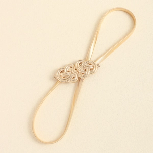Detailed view of elastic gold metal belt with textured interlocking double heart buckle
