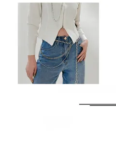 Detail of multi-layered silver metal waist chain layered over jeans and knit top