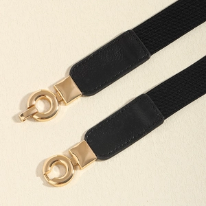 Détail d'une ceinture élastique noire avec boucle ronde en métal doré et embouts en cuir