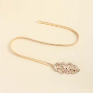 Detail of golden elastic metal waist chain featuring a twisted knot buckle for dresses
