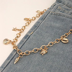 Chaîne de pantalon dorée avec breloques coquillages et tortues sur jean bleu