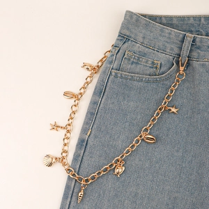 Détail de la chaîne de pantalon dorée avec breloques coquillages, étoiles de mer et tortues