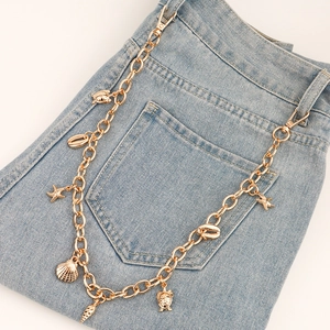 Chaîne de pantalon dorée avec pendentifs coquillages et étoiles de mer sur jean bleu