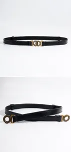 Detail van dunne zwarte riem met bronzen dubbele ring gesp en fijne stiksels erop