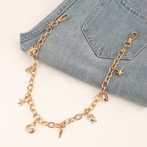 Détails d'une chaîne de jean dorée avec pendentifs coquillages et étoiles de mer