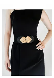 Close-up of black elastic waist belt featuring dual gold heart buckles with diamond texture