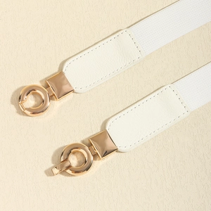 Détail de la boucle en métal doré clair et de la ceinture tressée élastique blanche