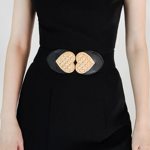 Detail of a women's black elastic waist belt with a golden heart-shaped metal buckle clasp