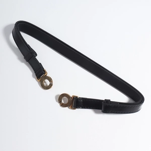 Detail van vintage gouden dubbele ringgesp met spiraaltextuur op zwarte leren riem