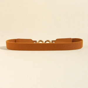Détail d'une ceinture élastique caramel avec boucle dorée à double anneau et texture tissu