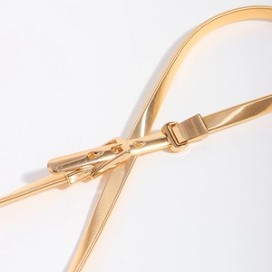 Close-up of golden elastic metal waist belt with polished rectangular buckle on white background