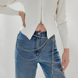 Detail of silver multilayered metal waist chain with triple draped layers on jeans
