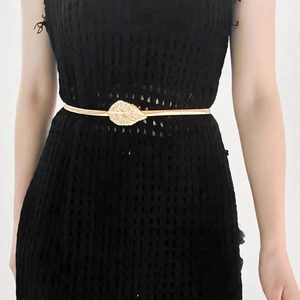 Close-up of golden leaf metal buckle on elastic waist chain belt worn on a black dress