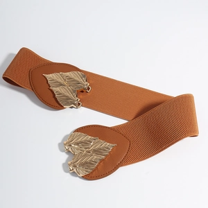 Detailed macro view of the golden metal leaf buckle on a caramel brown elastic waist belt