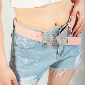 Gros plan sur ceinture en cuir rose avec boucle papillon argentée portée par un modèle