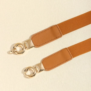 Gros plan d'une ceinture élastique caramel avec boucle métallique dorée circulaire