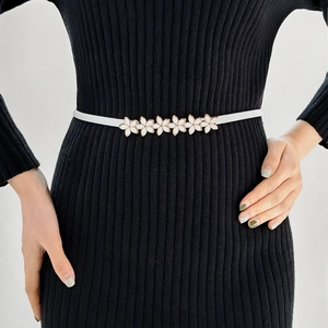 Detail of white floral elastic waist chain with gold trim on a black knitted dress