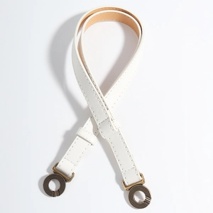 Detail van witte kunstlederen riem met vintage bronzen dubbele ringgespen en fijne textuur