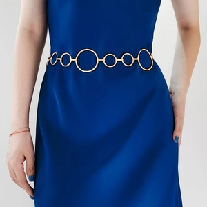 Detail einer goldenen runden Gliederkette als Gürtel auf einem dunklen Samtkleid für Mode