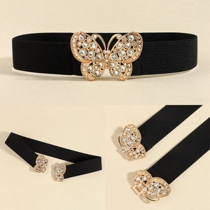 Detail of black elastic waist belt featuring a sparkling golden rhinestone butterfly buckle