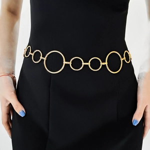 Detail einer ineinandergreifenden goldenen Metall-Taillenkette auf einem schwarzen Kleid