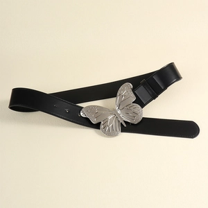 Détail d'une ceinture en cuir noir avec une grande boucle papillon argentée aux ailes polies