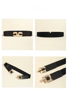Detail display of black elastic waist belt featuring golden double ring buckle and faux leather