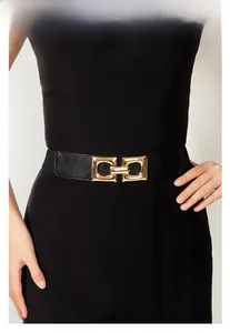 Close-up of women's black elastic waist belt with interlocking golden metal buckle